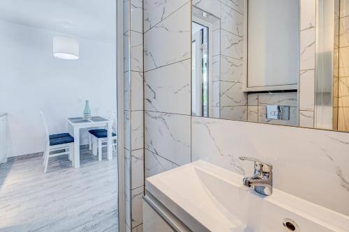 a white bathroom with a sink and a mirror at PROFIL Family House in Pogorzelica