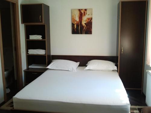 een slaapkamer met een groot wit bed en een boekenplank bij JR Motel in Otopeni