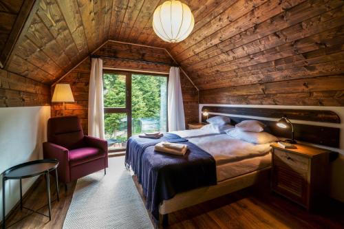 a bedroom with a bed and a chair and a window at Novosiele Residence in Bystre