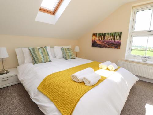 a bedroom with a large white bed with towels on it at Swallows Barn at Yew Tree Farm in Preston