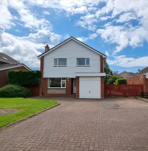 a white house with a garage on a driveway at Rozelle Villa in Ayr