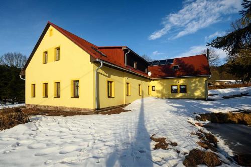 a yellow house with a red roof in the snow at Chalupa Křenov 62 in Bernartice