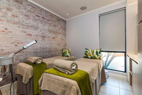una camera con due letti e un muro di mattoni di Waterfall Two-Bedroom Apartment a Midrand