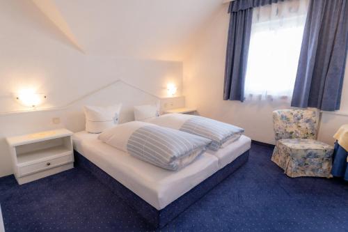 a bedroom with a bed and a chair and a window at Hotel Garni Hubertus-Nostalgie & Charme in Fulpmes