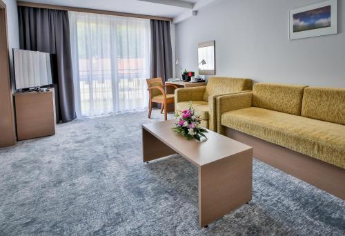 ein Wohnzimmer mit einem Sofa und einem Tisch in der Unterkunft LH Parkhotel Hluboka Nad Vltavou in Hluboká nad Vltavou