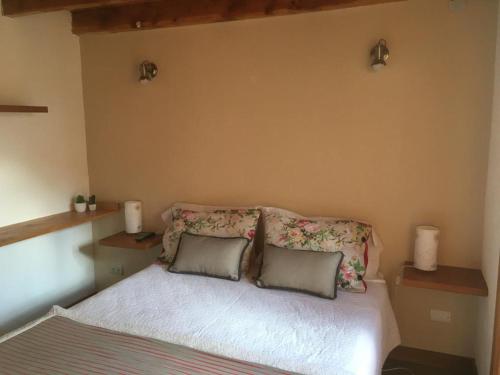 1 dormitorio con 1 cama con 2 almohadas en pequeña cabaña patagonica en San Martín de los Andes