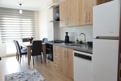 una cocina con armarios de madera y una mesa con sillas. en Kıvanç Residence en Trabzon