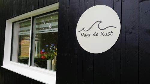 a sign on the side of a building with a window at Naar de kust in Hollum