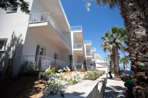 a white building with palm trees in front of it at TIKI BEACH STUDIOS in Nea Makri