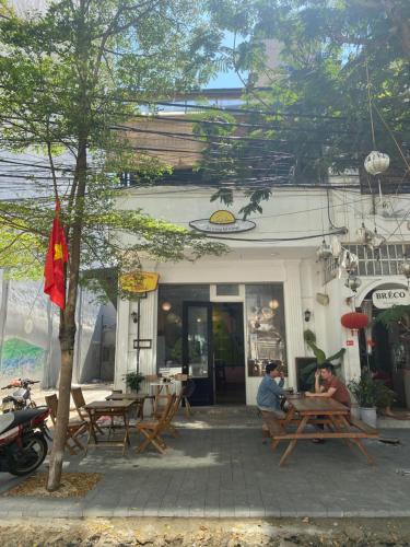 two people sitting at tables outside of a restaurant at Light House Hostel in Da Nang