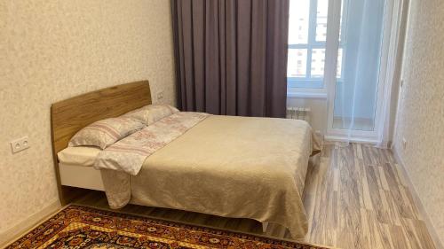 Schlafzimmer mit einem Bett, einem Fenster und einem Teppich in der Unterkunft ЖК Sat City блок С in Astana