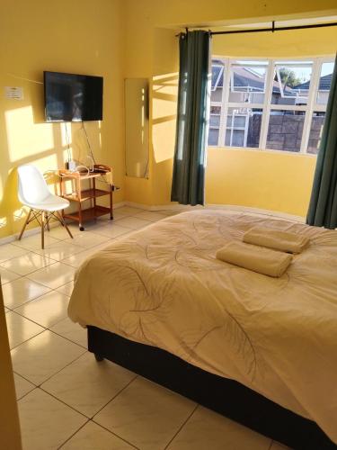 a bedroom with a bed and a chair and a television at Jacmo Guest house in Cape Town