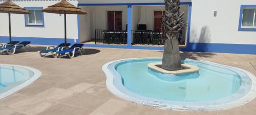 a pool with a palm tree in the middle of a building at Casa Almeida in Vimieiro