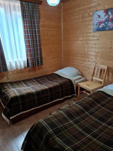 a room with two beds and a chair and a window at Guest House Shina in Omalo