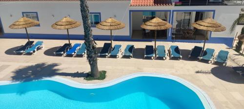 a swimming pool with chairs and umbrellas at Casa Almeida in Vimieiro