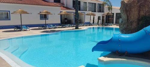 a large blue swimming pool with chairs and umbrellas at Casa Almeida in Vimieiro