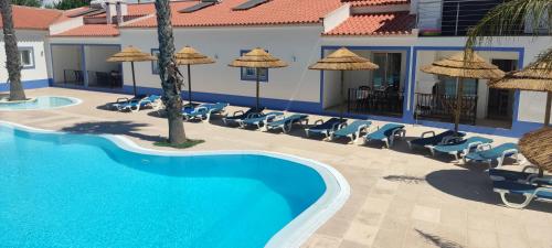 a pool at a hotel with chairs and umbrellas at Casa Almeida in Vimieiro