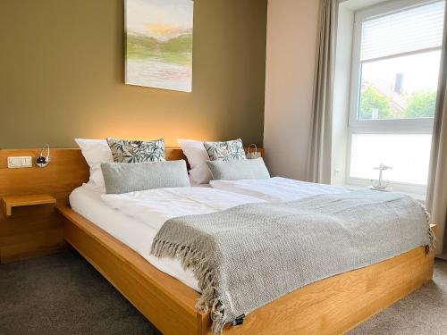 a large bed in a bedroom with a window at Hotel Grachtenhuus Greetsiel in Greetsiel