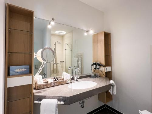 een badkamer met een wastafel en een spiegel bij Hotel Grachtenhuus Greetsiel in Greetsiel
