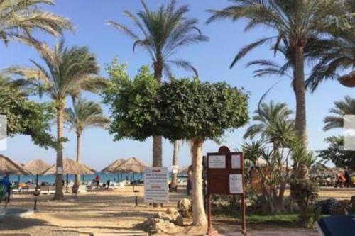 a resort with palm trees and a beach with a sign at Private chalte Palmera sokhna family in Ain Sokhna