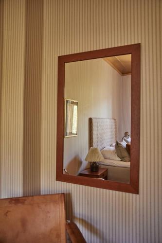 a mirror reflecting a bedroom with a bed and a chair at Rye115 Hotel in Copenhagen