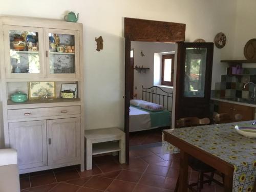 a kitchen with a table and a room with a bed at Su Saucu in Dorgali