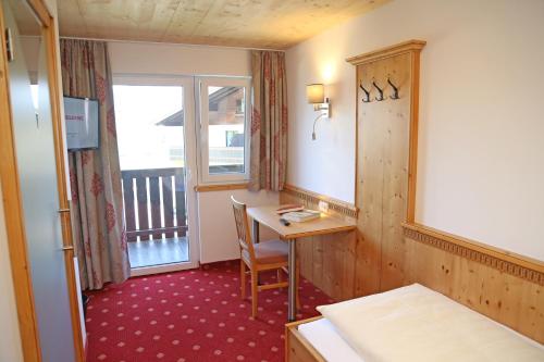 a room with a desk and a bed and a window at Hotel Quehenberger in Maishofen
