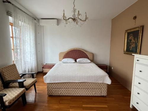 a bedroom with a bed and two chairs and a chandelier at Hiša Kapitelj in Novo Mesto