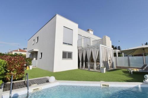 una casa blanca con piscina frente a ella en Villa Pura Vida with pool, en Savudrija