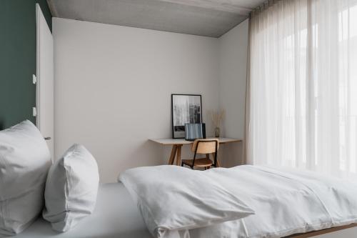 a white bedroom with a bed and a desk at CLOUD N°7 STUDIOS in Tübingen