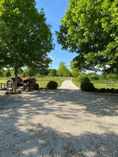 un tractor estacionado en un camino de grava junto a un árbol en Gite Le pigonnier Ecogite Le Luquet Saint Beauzeil 82150, en Saint-Beauzeil