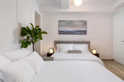 two white beds in a white bedroom with two lamps at Studio apartments in center of Opatija in Opatija