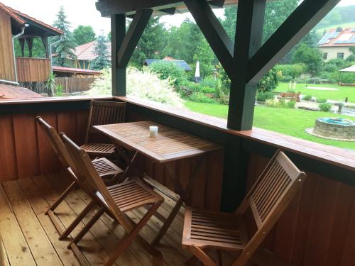 einen Holztisch und Stühle auf einer Veranda mit einem Fenster in der Unterkunft Landkulturhof Glücksbringer in Rudolstadt