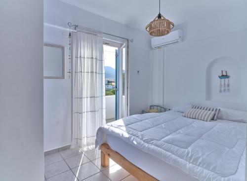 biała sypialnia z dużym łóżkiem i oknem w obiekcie Ifestos home with private veranda, Paros w mieście Logaras