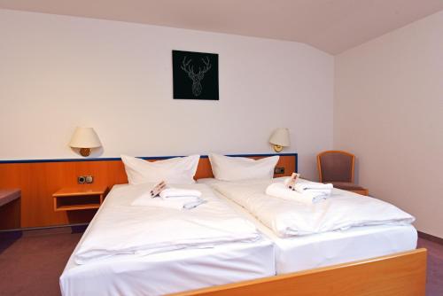 a large white bed with two white towels on it at Landhotel Der Distelhof mit Scheunencafé in Dillstädt