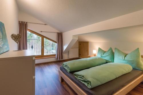 een slaapkamer met een bed met groene kussens erop bij Appartement Waldmoos in Ellmau