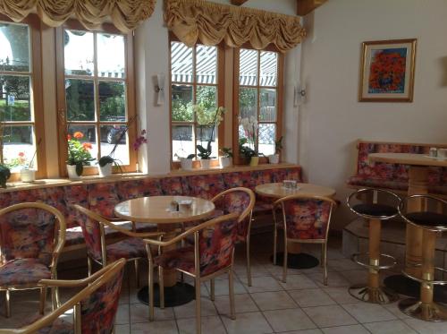 un restaurant avec des tables, des chaises et des fenêtres dans l'établissement Garni Pineta, à San Martino in Badia