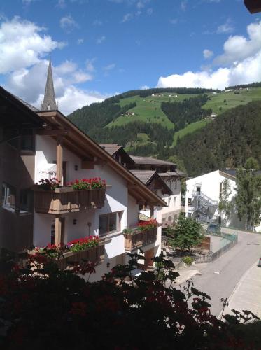 a building with flower boxes and a church at Garni Pineta in San Martino in Badia