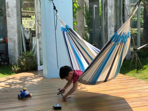 a little boy playing with a toy in a hammock at Mooning the Hill in Manzhou