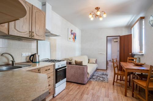 cocina y sala de estar con mesa y sofá en Aleksandrit Guest house, en Adler