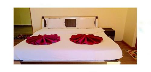 a white bed with two red roses on it at Orion Home in Leh
