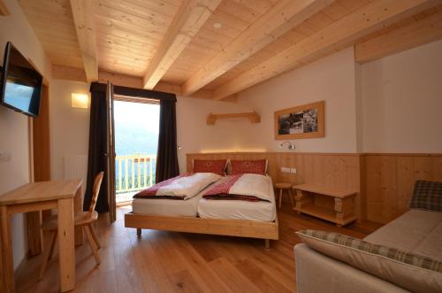 1 dormitorio con cama, escritorio y ventana en Agritur Majon da Mont, en Vigo di Fassa