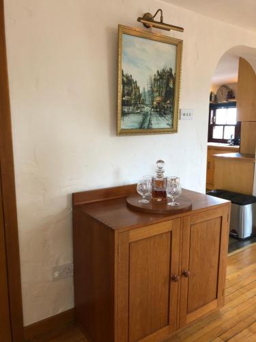 a wooden cabinet in a kitchen with a picture on the wall at The Coach House in Skelmorlie