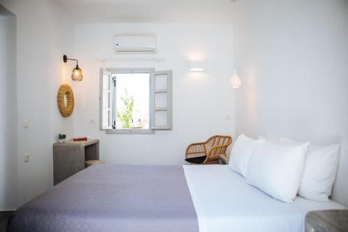 a white bedroom with a bed and a window at Aetheria Villas in Oia