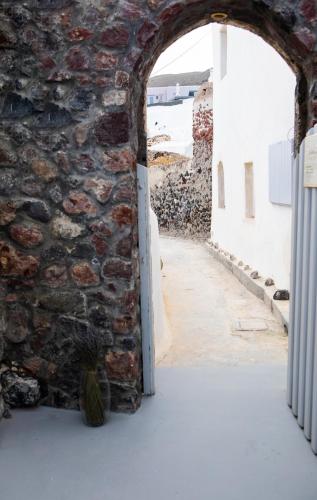 an archway in a stone wall with a vase in the doorway at Aetheria Villas in Oia