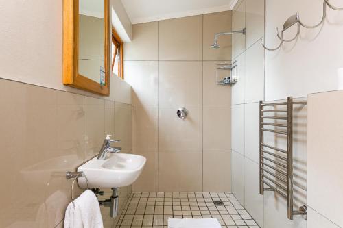 a bathroom with a sink and a shower at Camps Bay Village - Stone Cottages in Cape Town