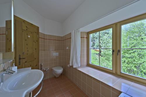 een badkamer met een wastafel, een toilet en een raam bij Chesa Domiziana - Samedan in Samedan