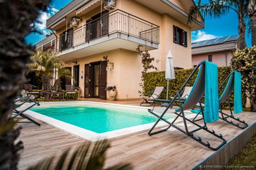 - une piscine avec 2 chaises et une maison dans l'établissement Casa vacanze ETNA COCUS, à Santa Venerina