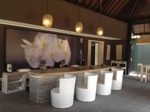 a bar with white chairs and flowers on the wall at Katala Suites and Villas in Sanur