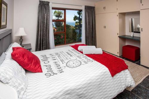 a bedroom with a large bed with red pillows at 2 Bedroom Holiday Flat in Dana Bay in Mossel Bay